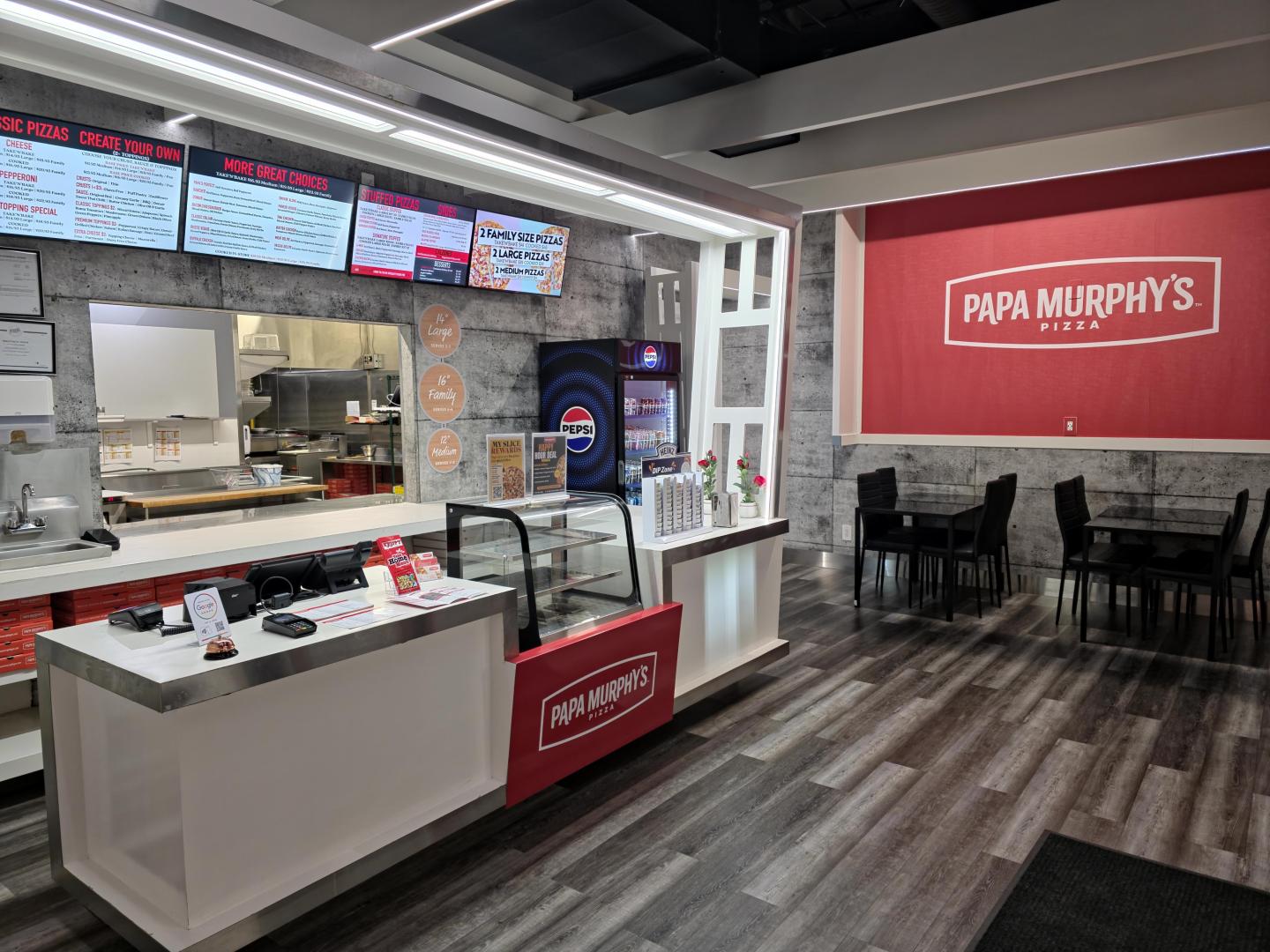 Pizza restaurant counter and seating area with menu screens and a red accent wall.