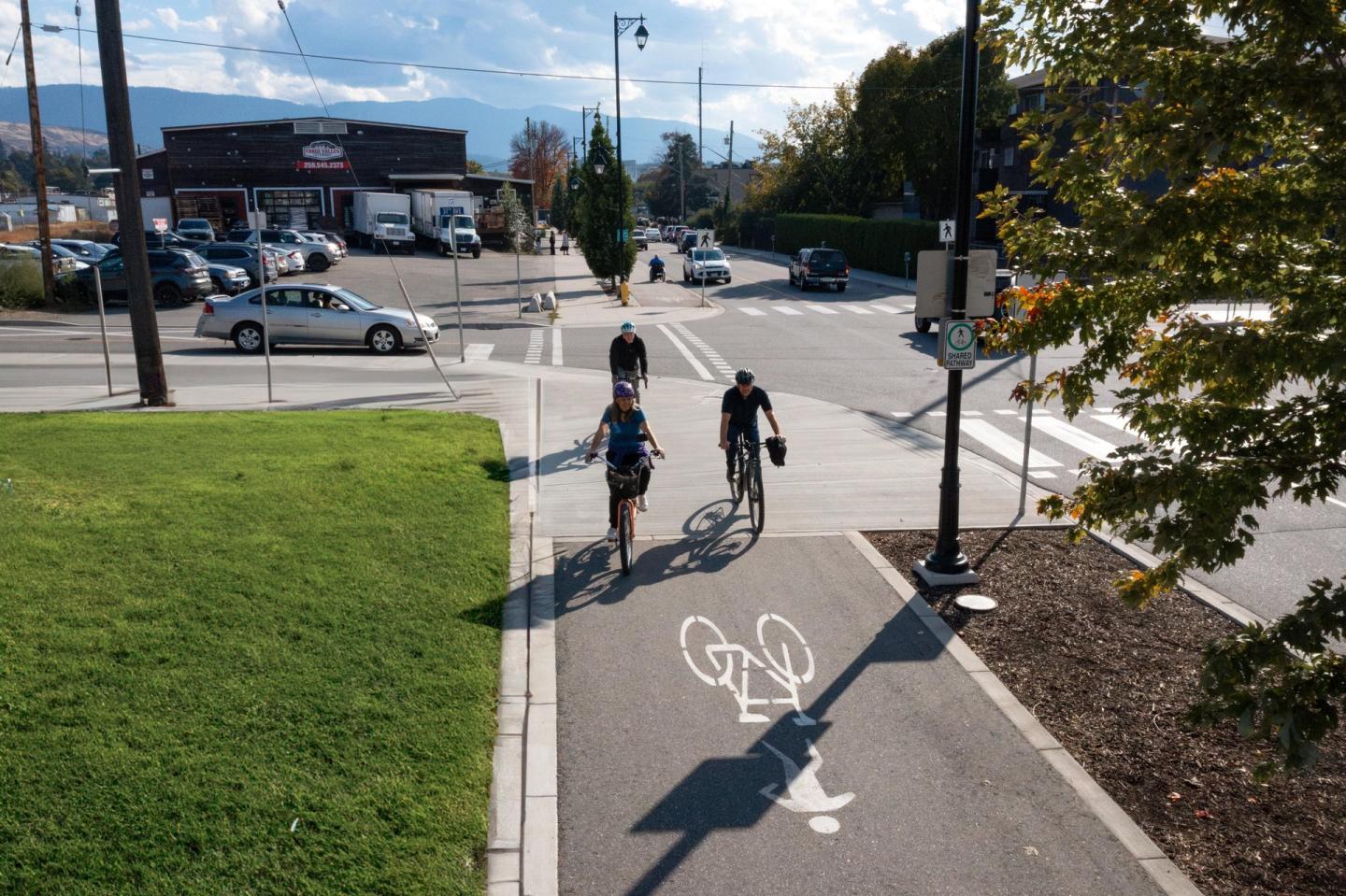 Cyclists ride on a sunny city bike path.