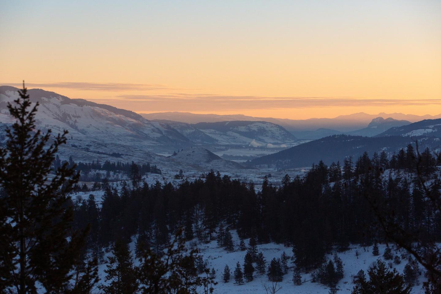 Snow-covered mountains at sunset with orange and purple sky.