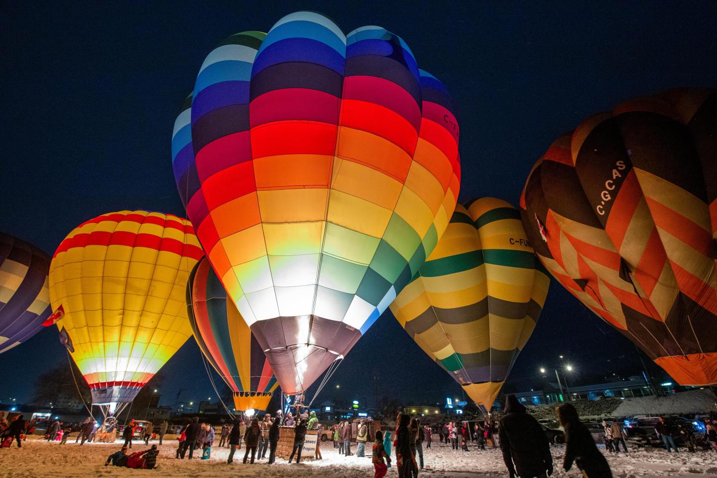 Hot air balloons illuminated at night with colorful patterns.