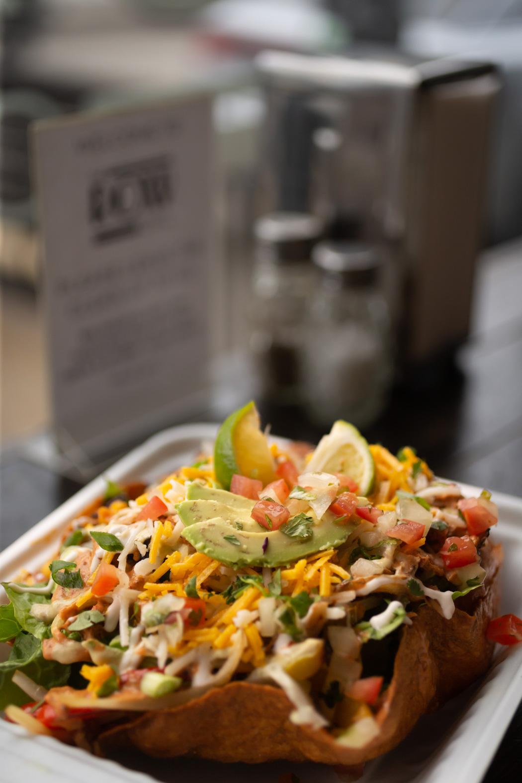 Taco salad with avocado, cheese, and lime in a crispy shell.