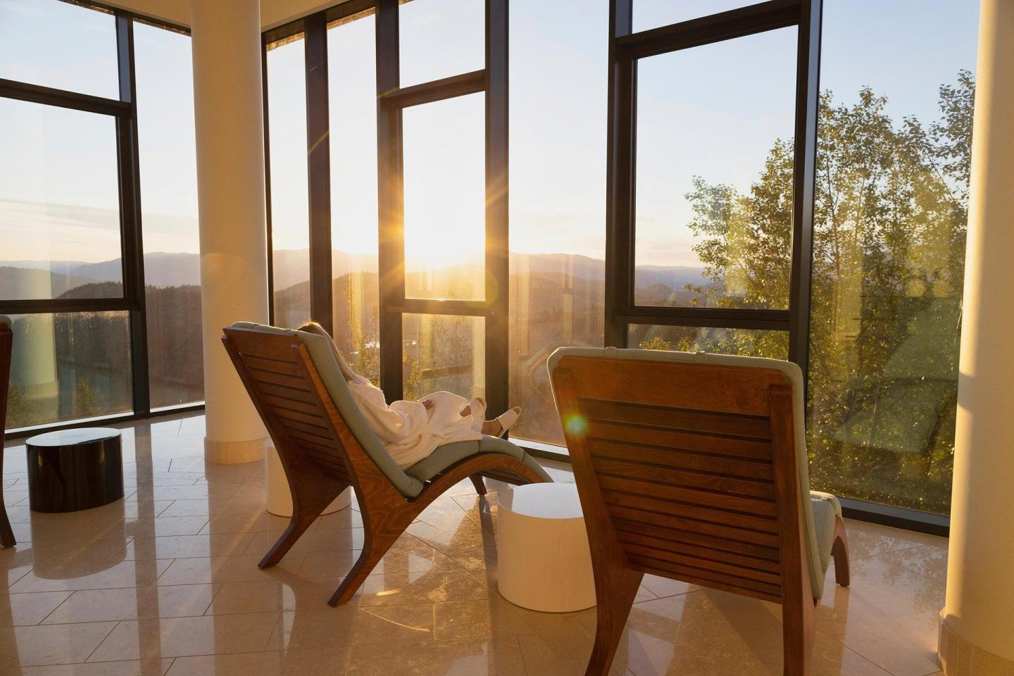 Sunlit room with two lounge chairs facing large windows and a scenic view.