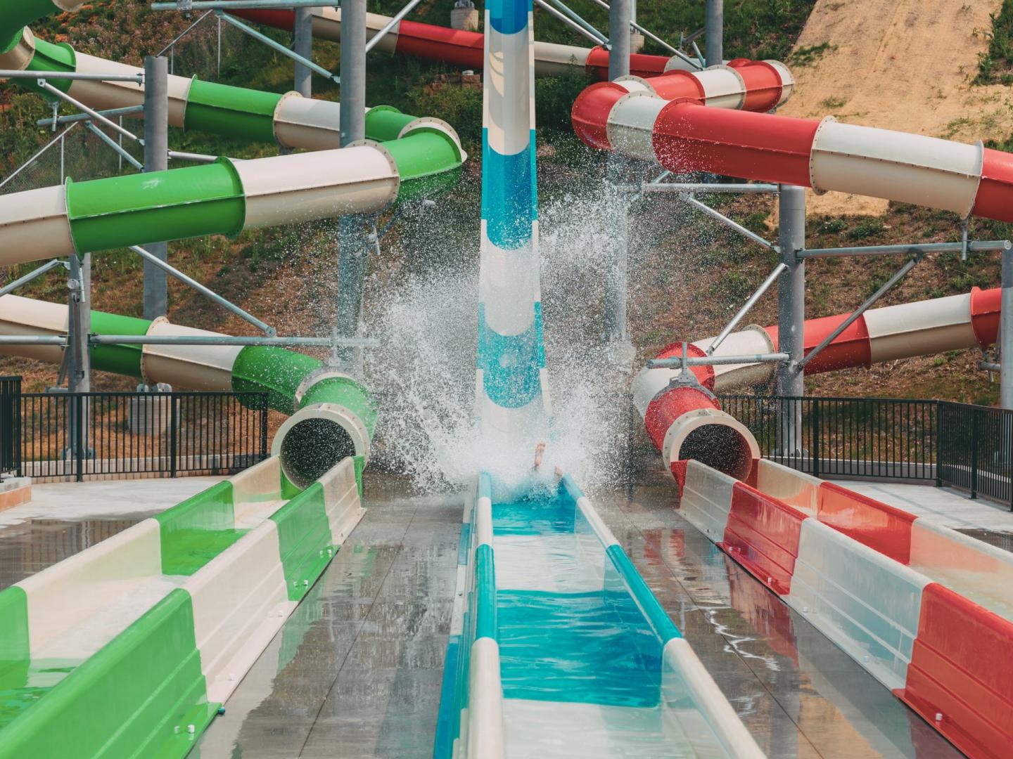 Colorful water slides with splash at pool's exit.