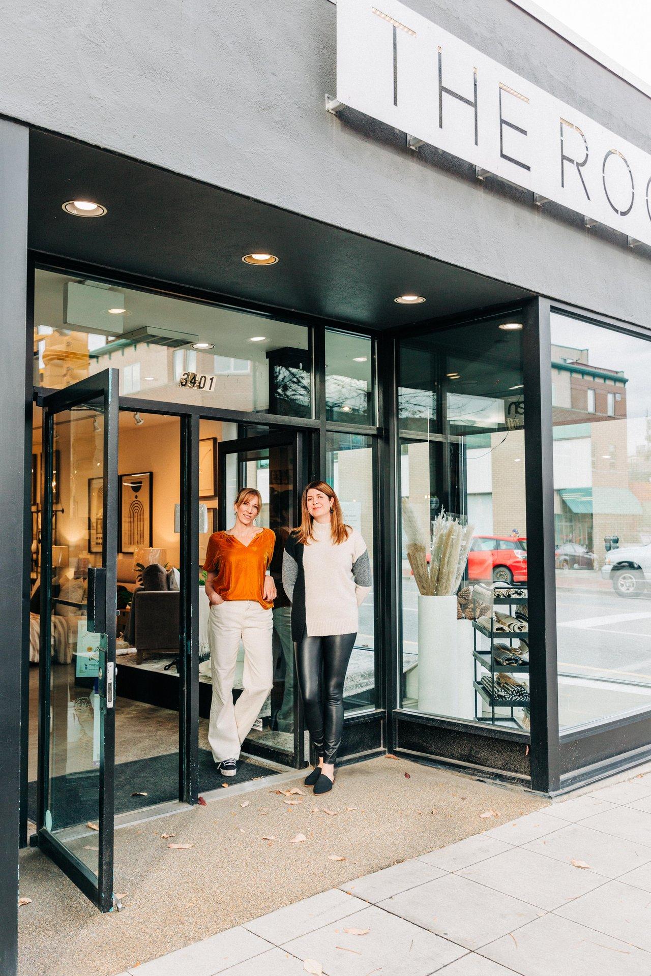 Two people standing outside a modern storefront, smiling.