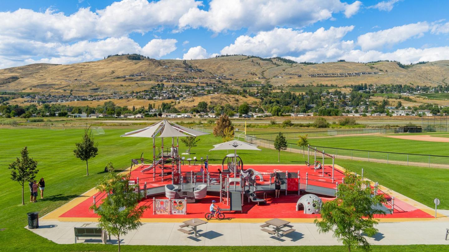 Colorful playground in a park with mountains in the background.