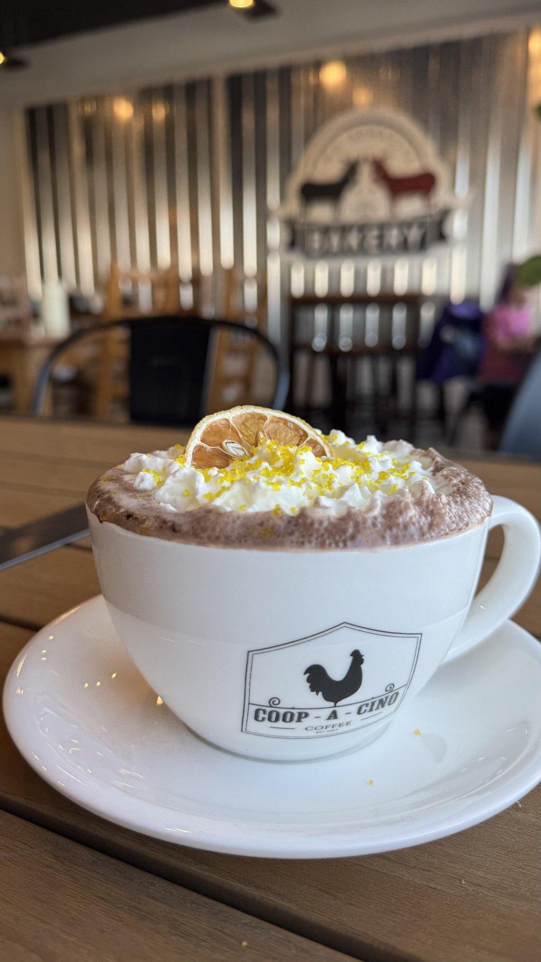Cup of hot chocolate with whipped cream and lemon zest on a cafe table.