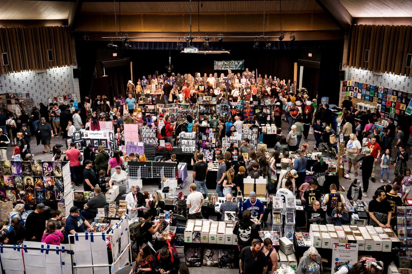 Crowded convention hall with booths and attendees browsing displays.