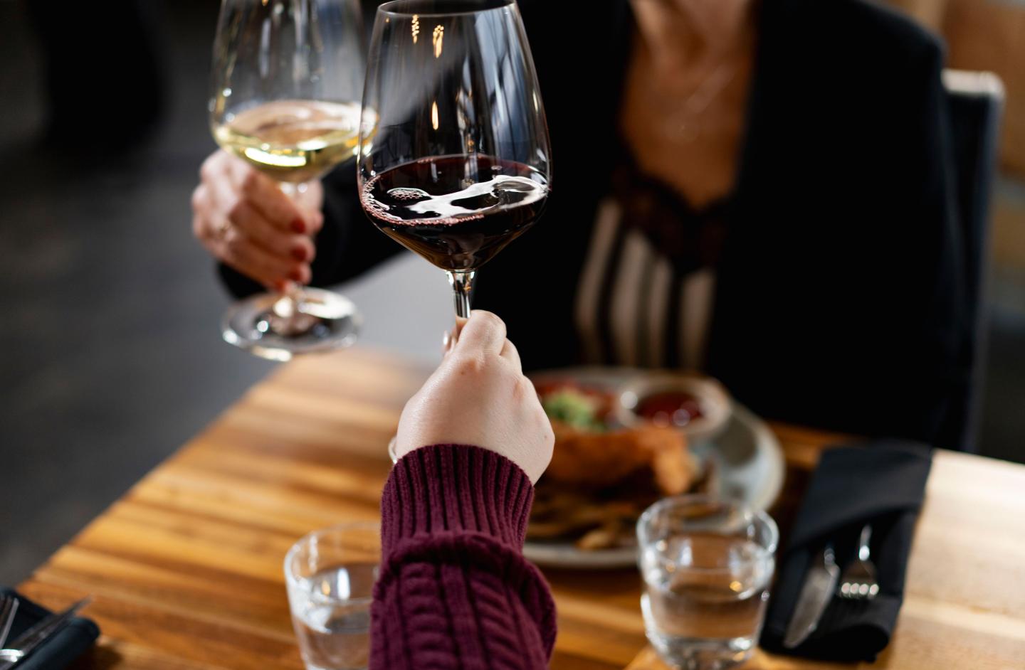 Two people cheersing at dinner.