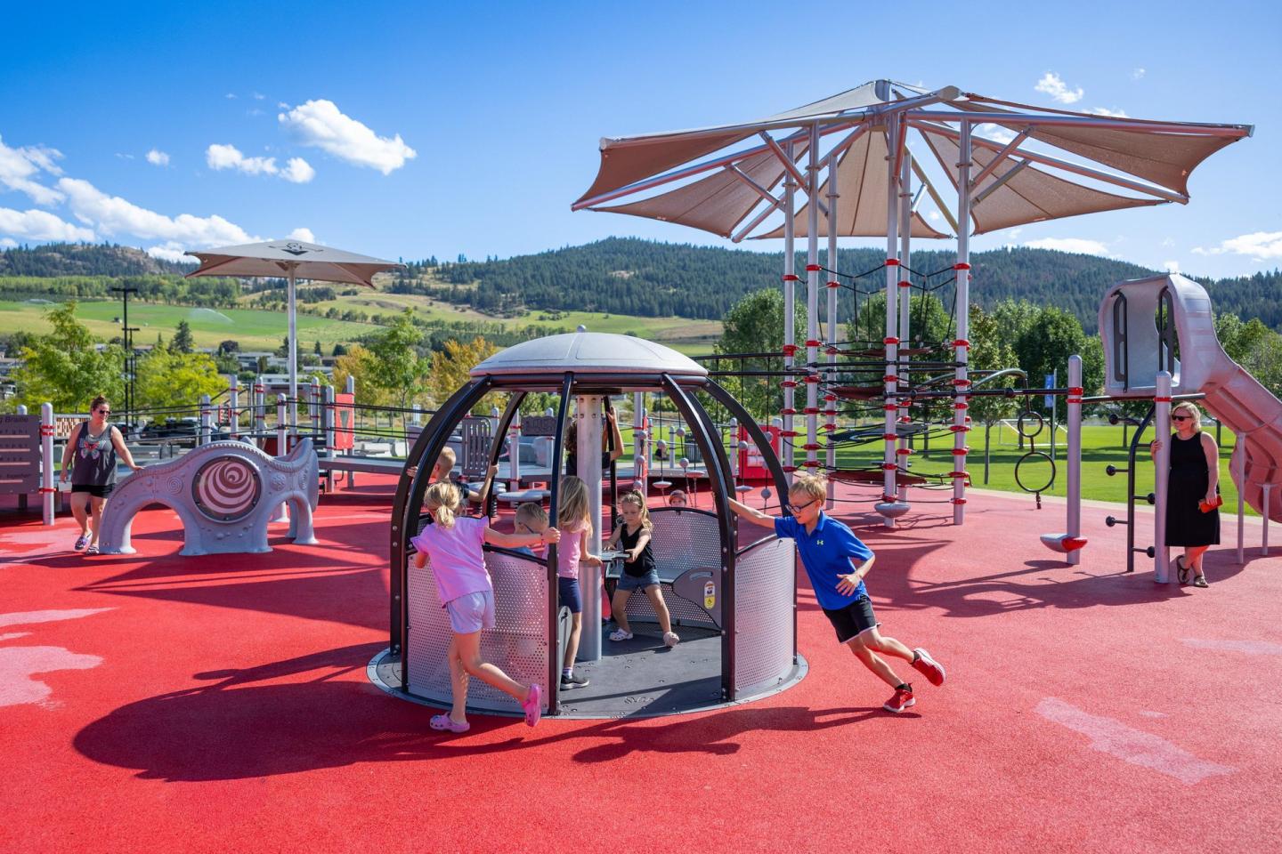 Children playing on a modern playground with hills in the background.