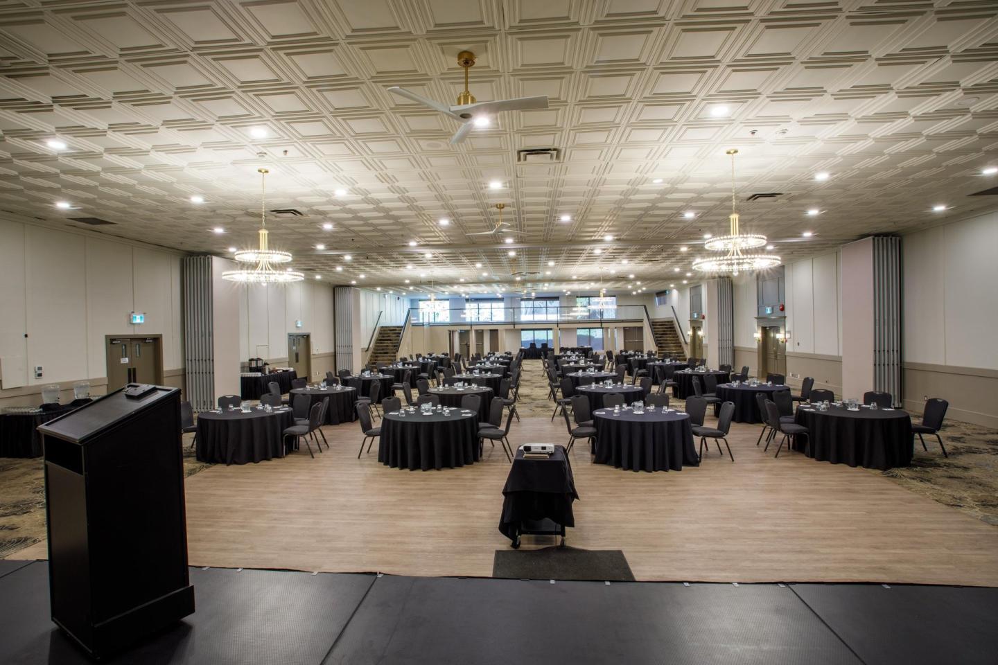 Spacious banquet hall with round tables and chandeliers.