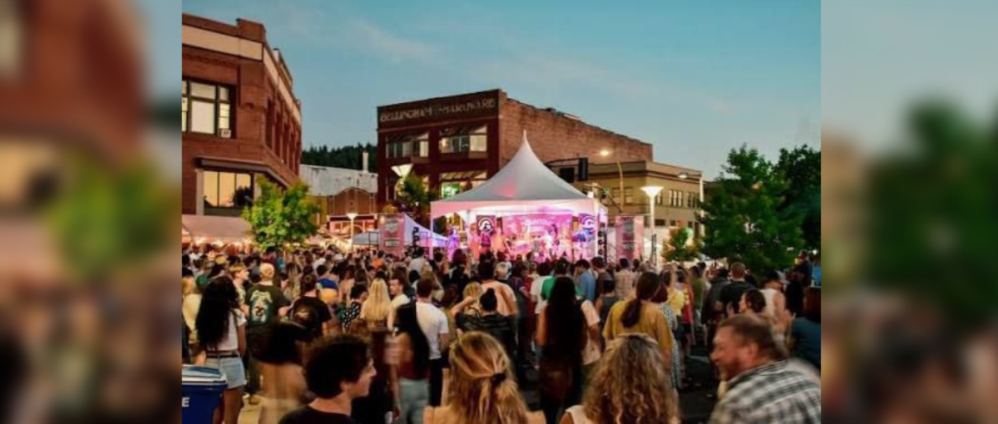 Crowd gathered for an outdoor concert under a tent at dusk.