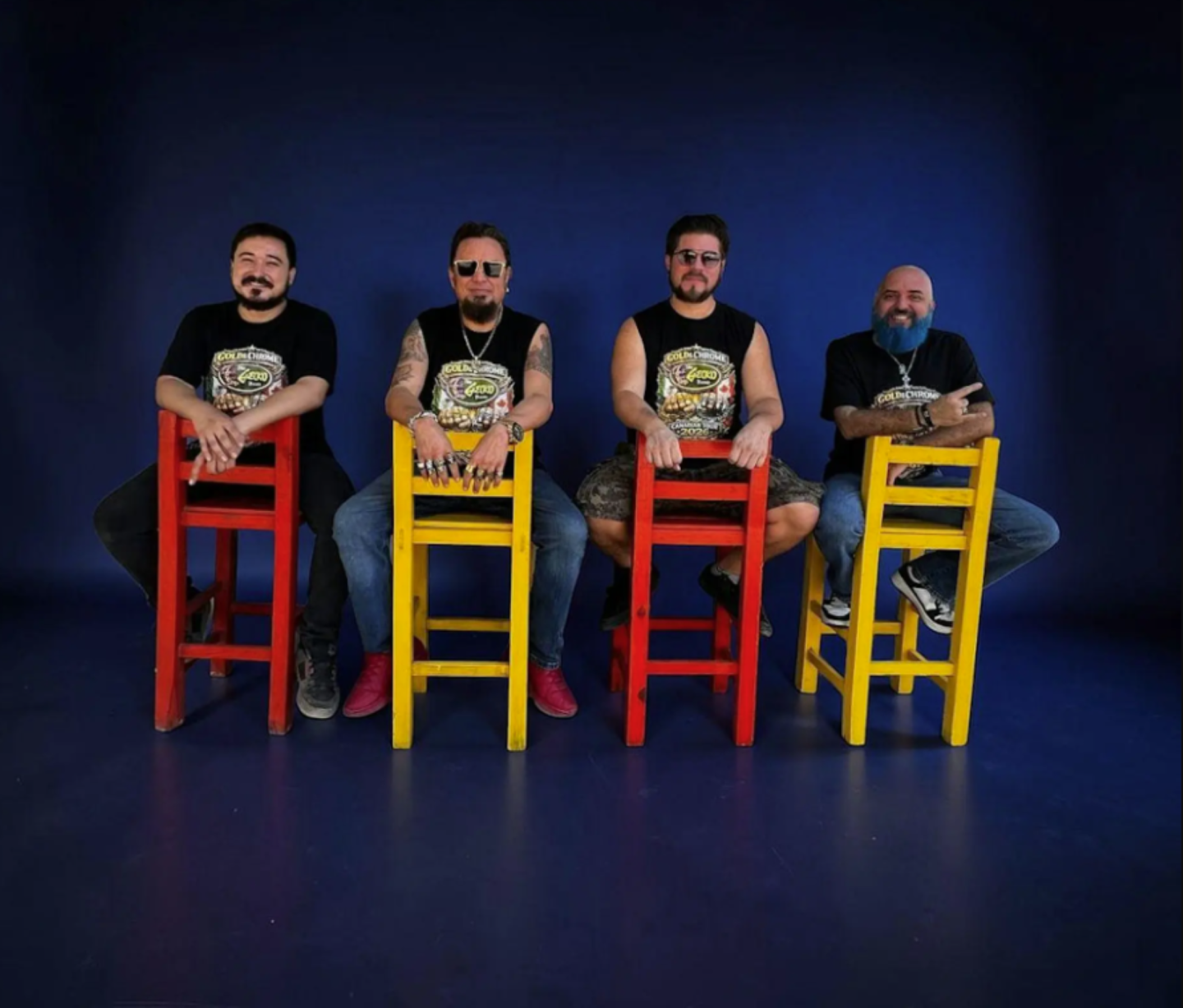 Four men seated on colorful chairs against a dark blue background.