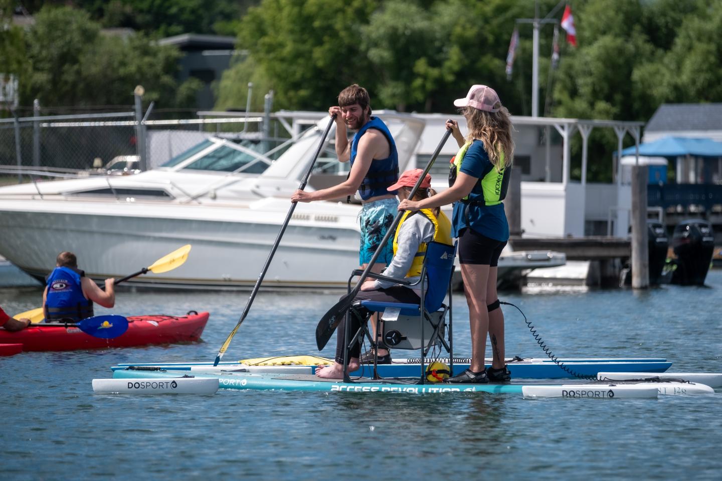 Three people paddleboarding on a lake near a dock.