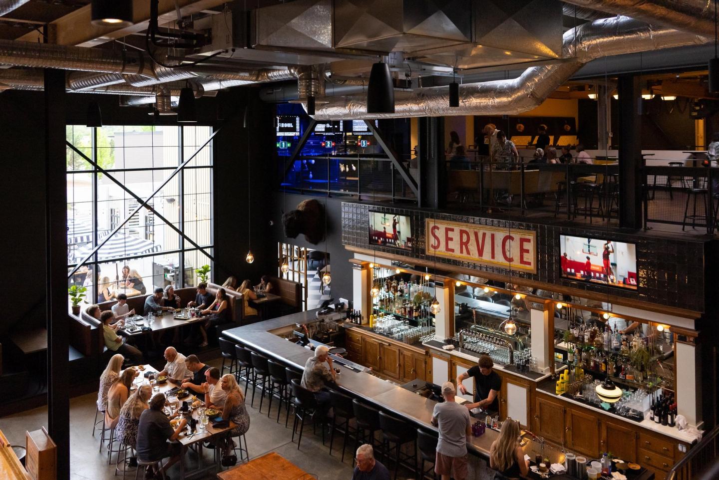 Industrial-style bar with patrons seated at tables and the counter.