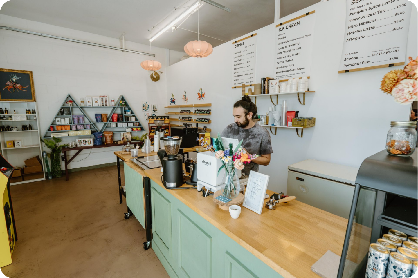 Barista working behind a wooden counter in a cozy, well-lit coffee shop.
