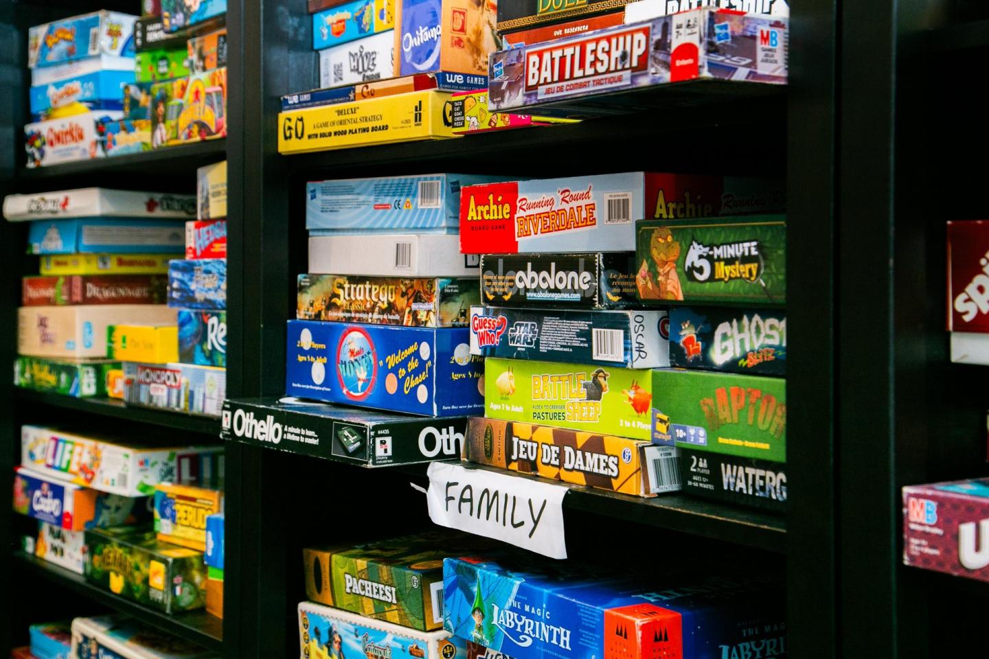 Board games stacked on black shelves labeled "FAMILY."