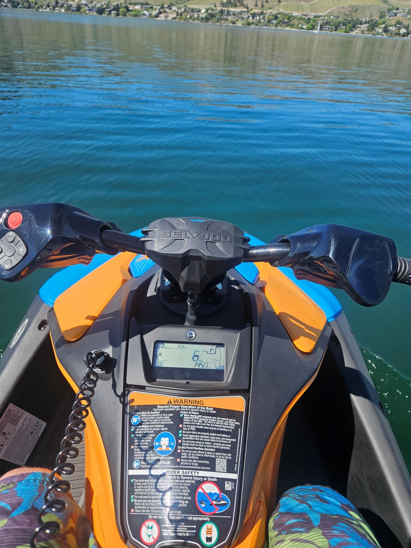 Jet ski dashboard on a calm lake with hills in the background.