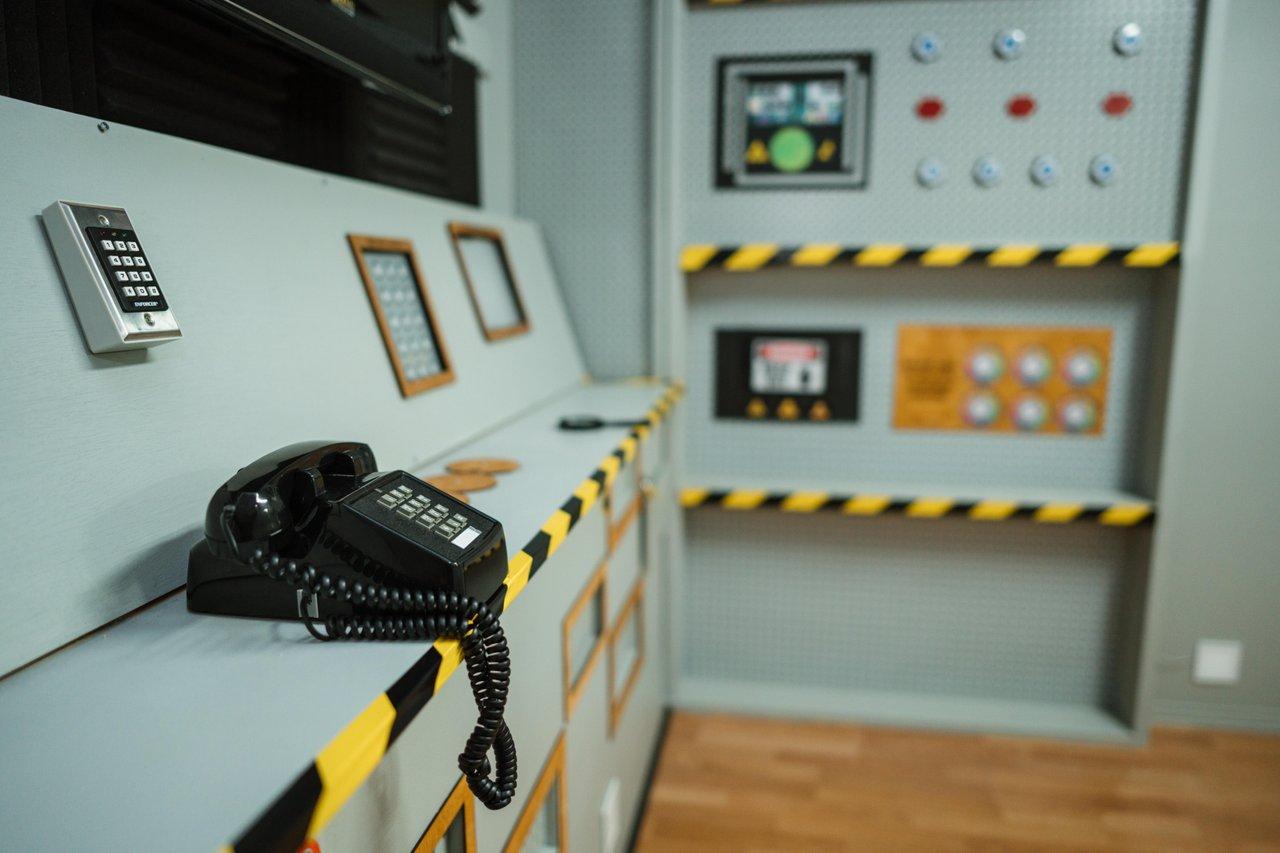 Control room with phone, dials, and switches on a panel.