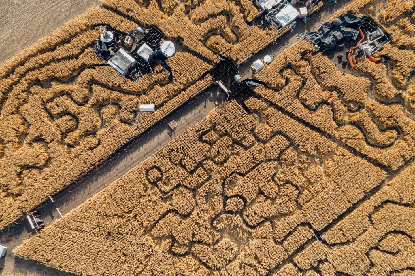 Aerial view of a road cutting through dry, cracked farmland with machinery nearby.