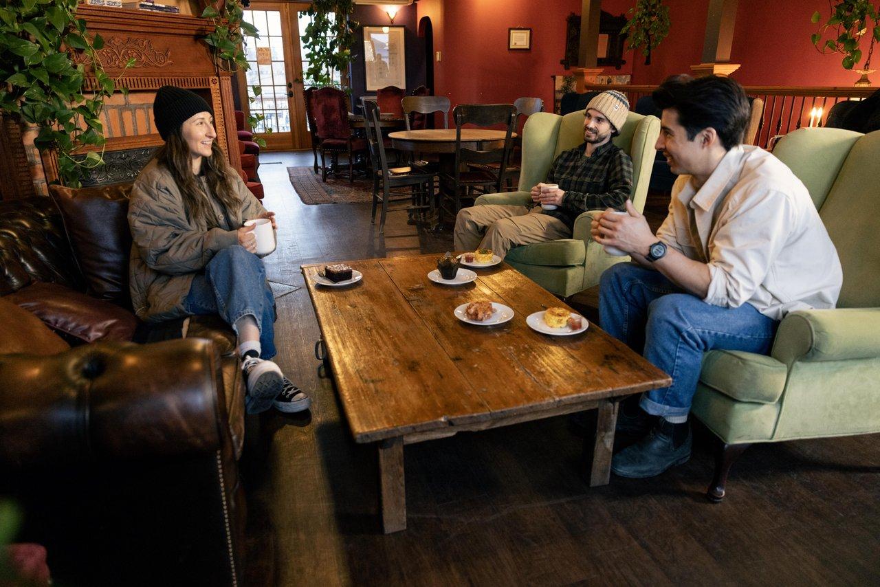 Three people chatting over coffee in a cozy living room.