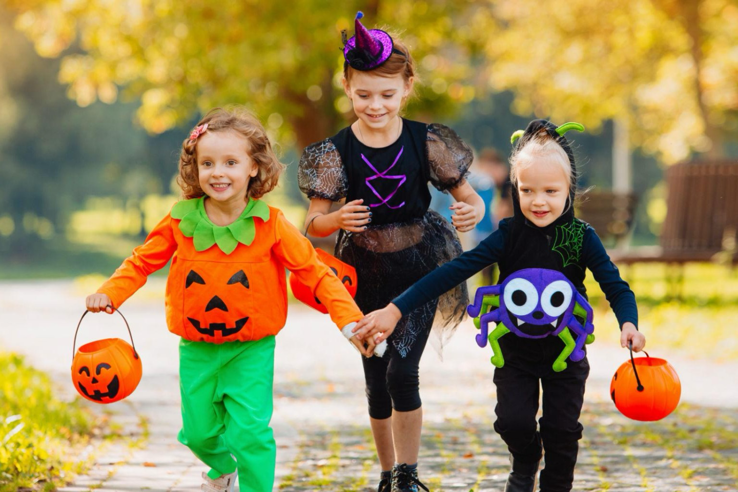 KIds in Halloween costumes carrying pumpkins