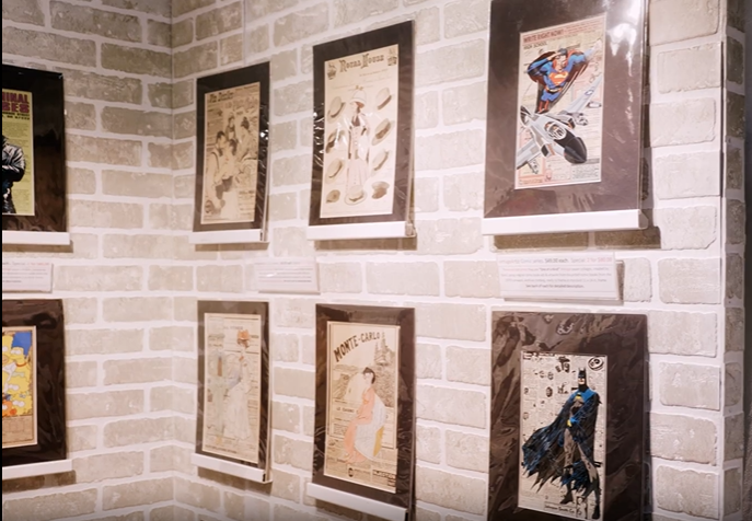 Framed artwork displayed on a white brick gallery wall.