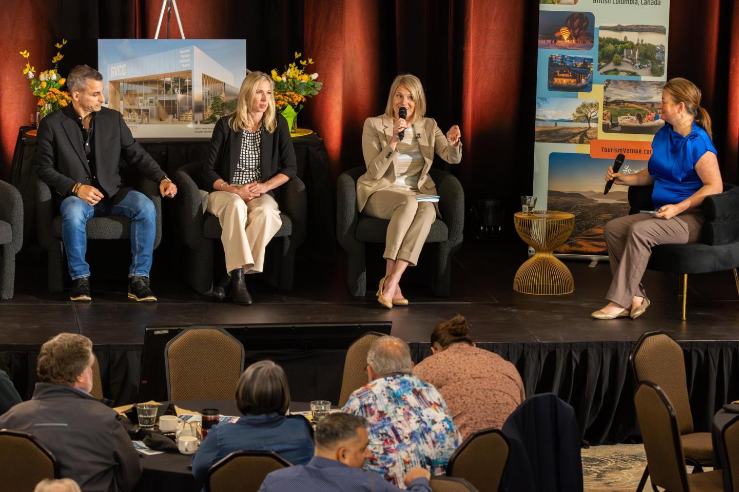 Panel discussion on a stage with four speakers and an audience.